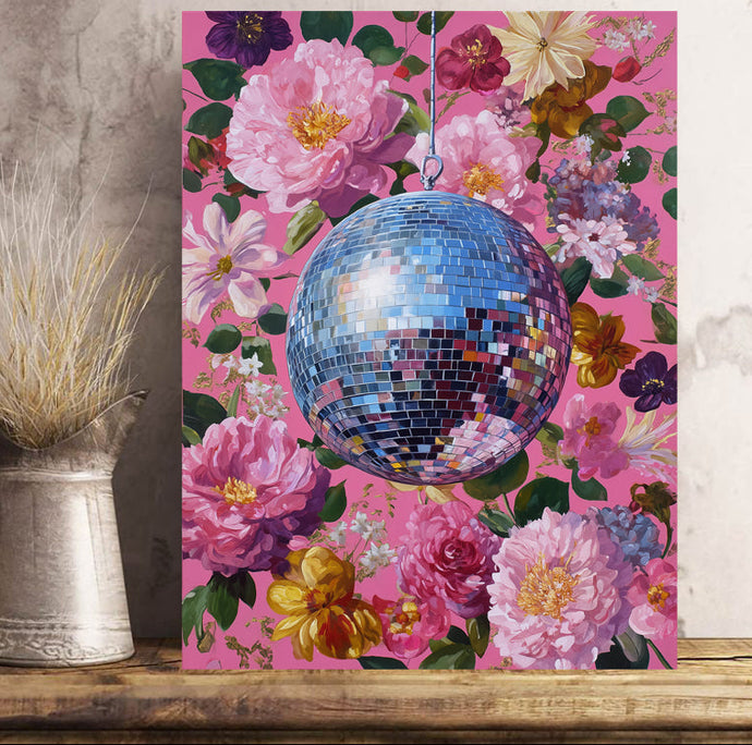 Canvas print with a disco ball and floral design on a pink background, placed on a wooden surface.